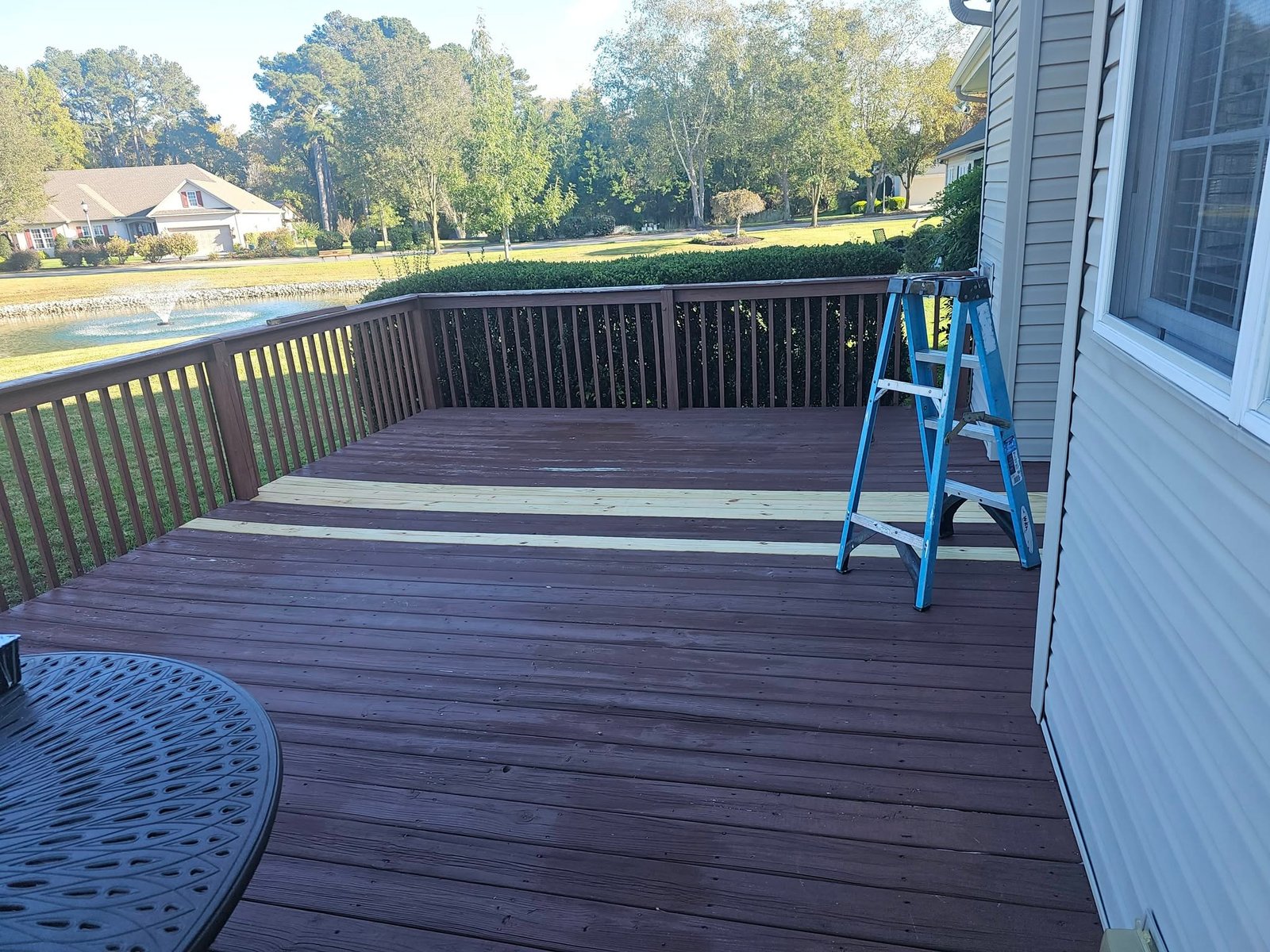 Wood deck construction with railing and ladder against the house