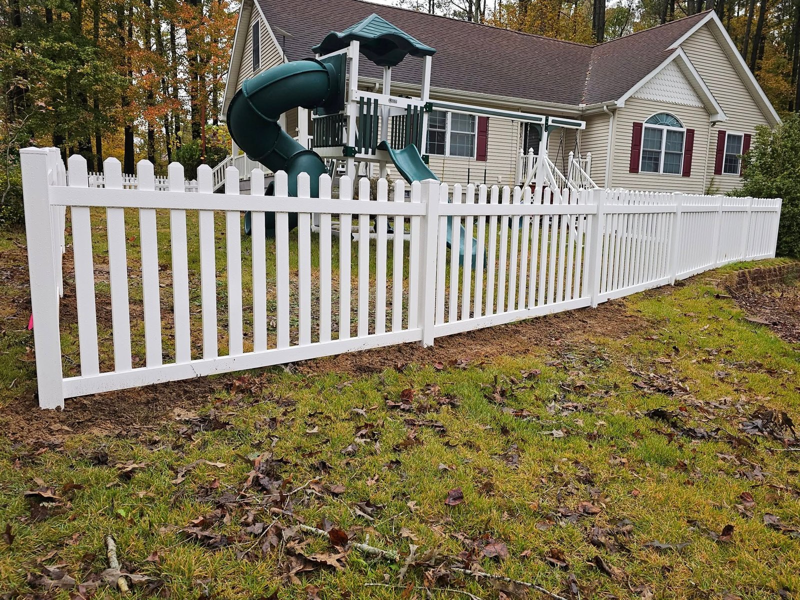 White picket fence around a yard with a children's playset