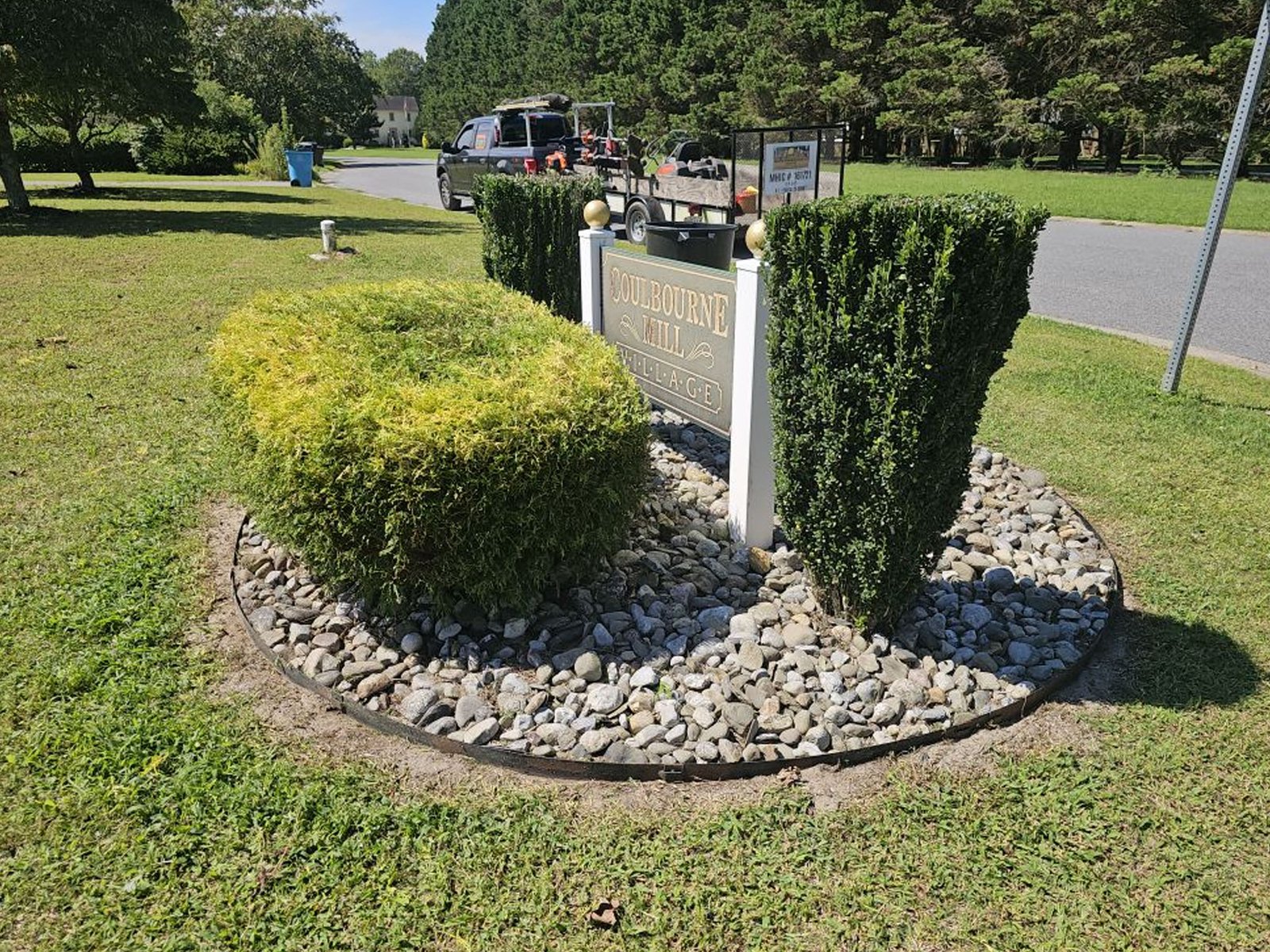 Landscaped entrance sign area with trimmed bushes and mulch