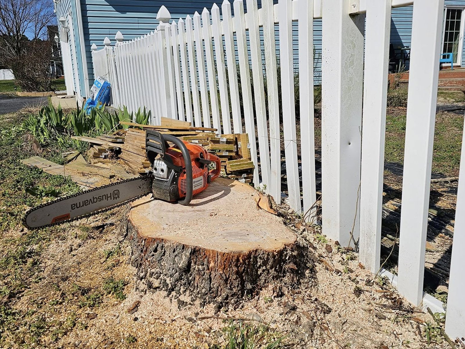 White picket fence with a tree stump nearby