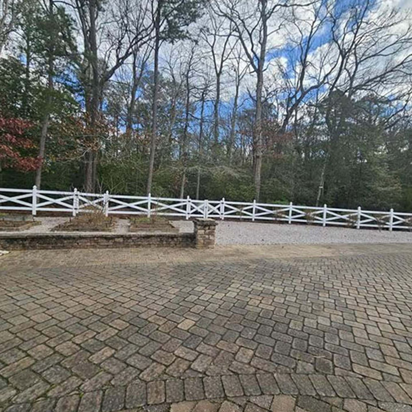 Paver driveway and walkway with white fence and trees